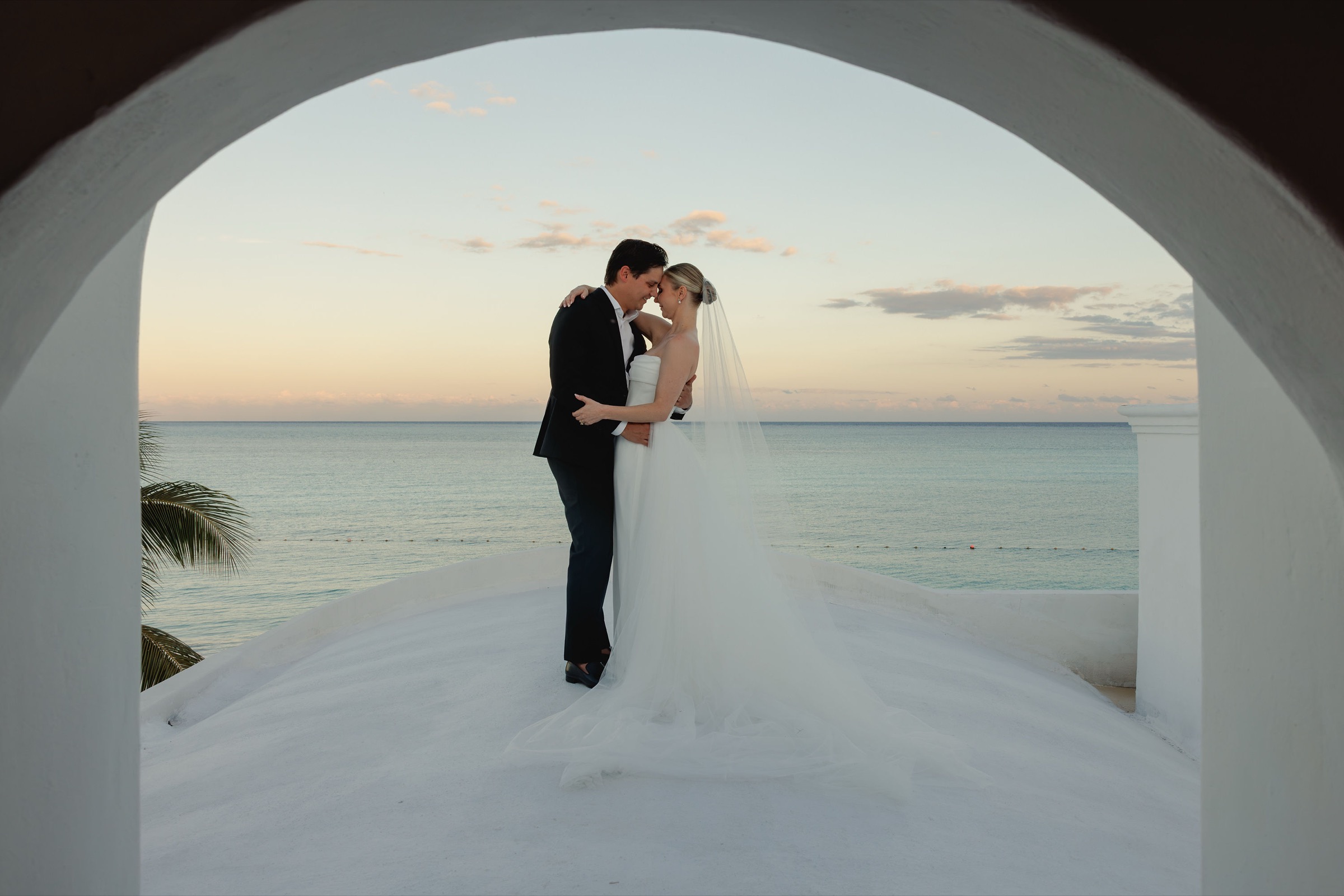 Cara & Joseph wedding at Chablé Maroma — the couple under a seafront arch at sunset